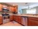 Contemporary kitchen with stainless steel appliances, granite countertops, wood cabinets, and pass through window to living area at 16215 Sw 15Th Ct, Ocala, FL 34473