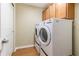 Laundry room with modern white washer and dryer units, wood-look flooring, and overhead storage cabinets at 16215 Sw 15Th Ct, Ocala, FL 34473