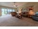 Comfortable living room with neutral carpet, ceiling fan, and access to outdoor patio through sliding glass doors at 16215 Sw 15Th Ct, Ocala, FL 34473