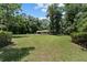 Expansive front yard showcases the home nestled within a lush, green landscape and tall trees at 19130 Nw 60Th Ave, Reddick, FL 32686
