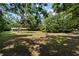 Picturesque view of a home surrounded by mature trees and a sprawling lawn under a blue sky at 19130 Nw 60Th Ave, Reddick, FL 32686