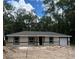 New construction home with neutral paint, dark trim, and attached one-car garage in a wooded setting at 20769 Sw Oriole Dr, Dunnellon, FL 34431