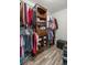 Walk-in closet featuring wood-look flooring, shelves, and rods holding various clothing items at 28 Hemlock Radial Loop, Ocala, FL 34472