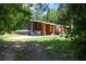 A view of the outbuilding with screened porch, painted orange, in a partially wooded area at 4501 Detour Rd, Haines City, FL 33844