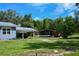 View of blue house with covered parking area, grass yard, and orange outbuilding at 4501 Detour Rd, Haines City, FL 33844