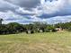 View across green grass field with various outbuildings under partly cloudy sky at 4501 Detour Rd, Haines City, FL 33844