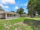 Backyard with a sunroom, a covered seating area, and green grass at 4660 Se 142Nd Ln, Summerfield, FL 34491