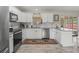 Modern kitchen features white cabinetry, stainless steel appliances, and granite countertops with tiled backsplash at 4660 Se 142Nd Ln, Summerfield, FL 34491