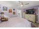 A large primary bedroom with a ceiling fan, TV, and an en-suite bathroom is perfect for relaxing at 4660 Se 142Nd Ln, Summerfield, FL 34491