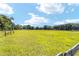Wide shot of the sunny acreage featuring a wooden fence that runs along the edge of the yard at 475 Ne 155Th Pl, Citra, FL 32113
