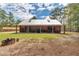Exterior backyard view of log cabin with metal roof, covered porch, and natural landscape at 5630 Se 183Rd Avenue Rd, Ocklawaha, FL 32179