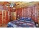 Warm bedroom featuring wood paneling, a ceiling fan, and cozy bedding at 5630 Se 183Rd Avenue Rd, Ocklawaha, FL 32179