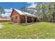 Exterior view of log cabin showcasing metal roof, covered porch, and landscaped yard at 5630 Se 183Rd Avenue Rd, Ocklawaha, FL 32179