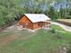 Log cabin exterior with lush lawn and gravel driveway, featuring a durable metal roof and a/c unit at 5630 Se 183Rd Avenue Rd, Ocklawaha, FL 32179