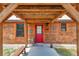Inviting front entry with wood framing, red door, and decorative details at 5630 Se 183Rd Avenue Rd, Ocklawaha, FL 32179