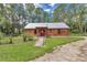 Cozy log cabin with metal roof, charming front yard, and a welcoming stone pathway to the red front door at 5630 Se 183Rd Avenue Rd, Ocklawaha, FL 32179