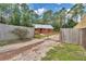 View of log cabin nestled behind a gated fence with a gravel driveway and flourishing foliage at 5630 Se 183Rd Avenue Rd, Ocklawaha, FL 32179