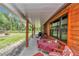 Under the covered porch shows rustic log columns, outdoor seating, and grill, with backyard in view at 5630 Se 183Rd Avenue Rd, Ocklawaha, FL 32179