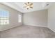 Spacious main bedroom featuring carpet flooring, a ceiling fan, and two windows for ample natural light at 6299 Sw 90Th St, Ocala, FL 34476