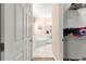 Bright bathroom featuring a soaking tub, neutral tile floors, and a glimpse of an organized walk-in closet at 6551 Se 11Th Loop, Ocala, FL 34472