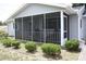 Enclosed porch with neutral-colored siding, white trim, and chairs, enhanced by landscaping at 8650 Sw 108Th Pl, Ocala, FL 34481