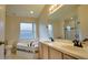 Bright bathroom with double sinks, a large mirror, a bathtub with decorative tile, and glass-enclosed shower at 949 Woodsong Way, Clermont, FL 34714