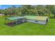 Aerial view of horse barn and attached equipment shelter with a large open grassy field surrounding the buildings at 975 Cr 542E, Bushnell, FL 33513
