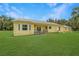 Expansive backyard featuring lush green grass and a charming yellow home at 975 Cr 542E, Bushnell, FL 33513
