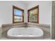 Close-up shot of soaking tub and two wood-framed windows at 975 Cr 542E, Bushnell, FL 33513