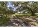 A tree-lined driveway leads to a charming home with a sprawling lawn and split rail fence at 975 Cr 542E, Bushnell, FL 33513