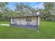 Charming white home with a screened-in porch surrounded by a lush green lawn and mature trees at 975 Cr 542E, Bushnell, FL 33513
