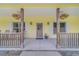 Covered front porch with rocking chairs, hanging flower baskets and decorative glass front door at 975 Cr 542E, Bushnell, FL 33513