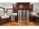 A view of the kitchen with stainless steel appliances, wooden cabinets, granite countertops, and hardwood flooring at 975 Cr 542E, Bushnell, FL 33513