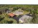 Aerial view showcasing a large property with multiple buildings, mature trees and a tennis court at 10835 Se Highway 464C, Ocklawaha, FL 32179