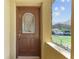 A decorative front door with glass panel leads to a home with a barn-like structure in the background at 10835 Se Highway 464C, Ocklawaha, FL 32179