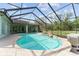 Enclosed pool area featuring a rock waterfall, in-ground pool, and a hot tub with a screened enclosure at 10835 Se Highway 464C, Ocklawaha, FL 32179