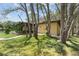 Home exterior with mature trees, screened porch, and walkway amidst a lush green lawn at 10835 Se Highway 464C, Ocklawaha, FL 32179