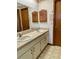 Bathroom featuring dual sinks, patterned linoleum, wallpaper, and ample cabinet space at 1112 Ne 130Th Ter, Silver Springs, FL 34488