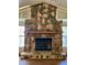 Close-up of a large stone fireplace with a wooden mantel and glass doors at 1112 Ne 130Th Ter, Silver Springs, FL 34488