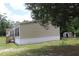 Side view of tan home highlighting black shutters and green lawn with a shed in distance at 11160 Nw 8Th Ln, Ocala, FL 34482