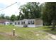 A tan single Gathering home boasts black shutters against a green lawn and backdrop of trees at 11160 Nw 8Th Ln, Ocala, FL 34482