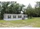 A tan home featuring black shutters and a welcoming front porch amidst a lush green lawn at 11160 Nw 8Th Ln, Ocala, FL 34482