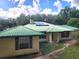 Back view of home featuring a green metal roof, light-colored siding, and solar panels at 17051 Ne 243Rd Place Rd, Fort Mc Coy, FL 32134