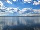Scenic lake view featuring calm waters under a sunny sky with scattered clouds at 17051 Ne 243Rd Place Rd, Fort Mc Coy, FL 32134