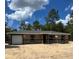 Single-story home boasts a classic design with a single-car garage and neutral color palette, set against a sunny sky at 21712 Sw Rainbow Lakes Blvd, Dunnellon, FL 34431