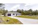 Charming single-story home featuring a modern exterior, a dark one-car garage, and a long concrete driveway at 23995 Nw Falcon Ave, Dunnellon, FL 34431