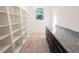 Spacious pantry with custom shelving, granite counters, and light wood-look tile flooring at 7 Hill Prince Dr, Ocala, FL 34482