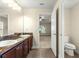 Bathroom showcasing a double vanity with wood cabinets, tile flooring, and open access to a bedroom at 8 Diamond Club Rd, Ocala, FL 34472
