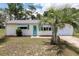 Charming single-story home with well-kept lawn, accented by palm trees and a delightful turquoise door and awnings at 8247 Sw 105Th Pl, Ocala, FL 34481