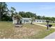 Quaint single-story home with a manicured lawn, palm trees, and a lovely turquoise door, offering curb appeal at 8247 Sw 105Th Pl, Ocala, FL 34481